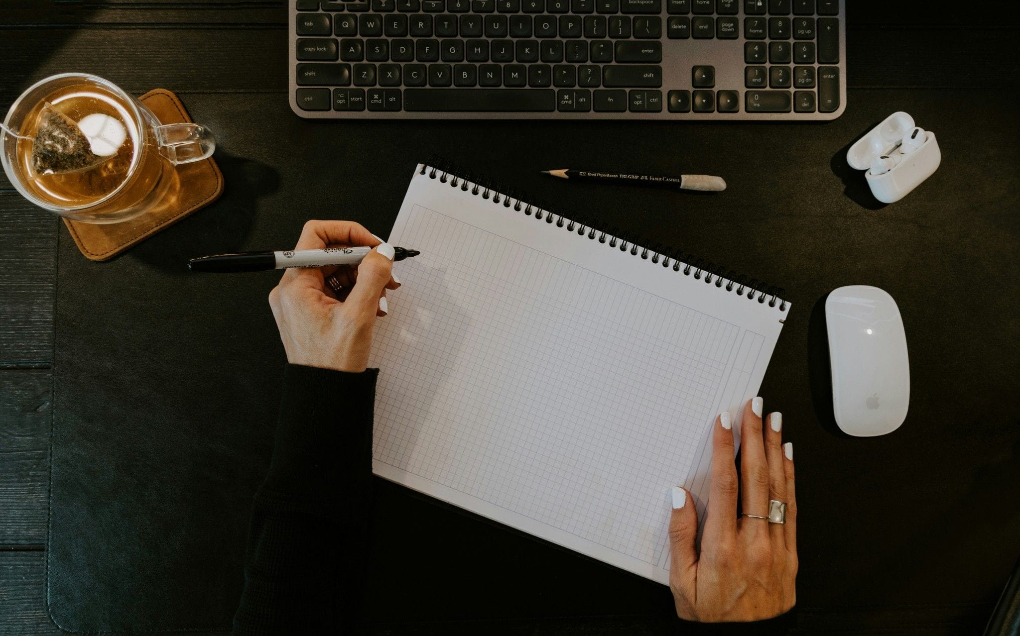 Person writing in a notebook next to a keyboard