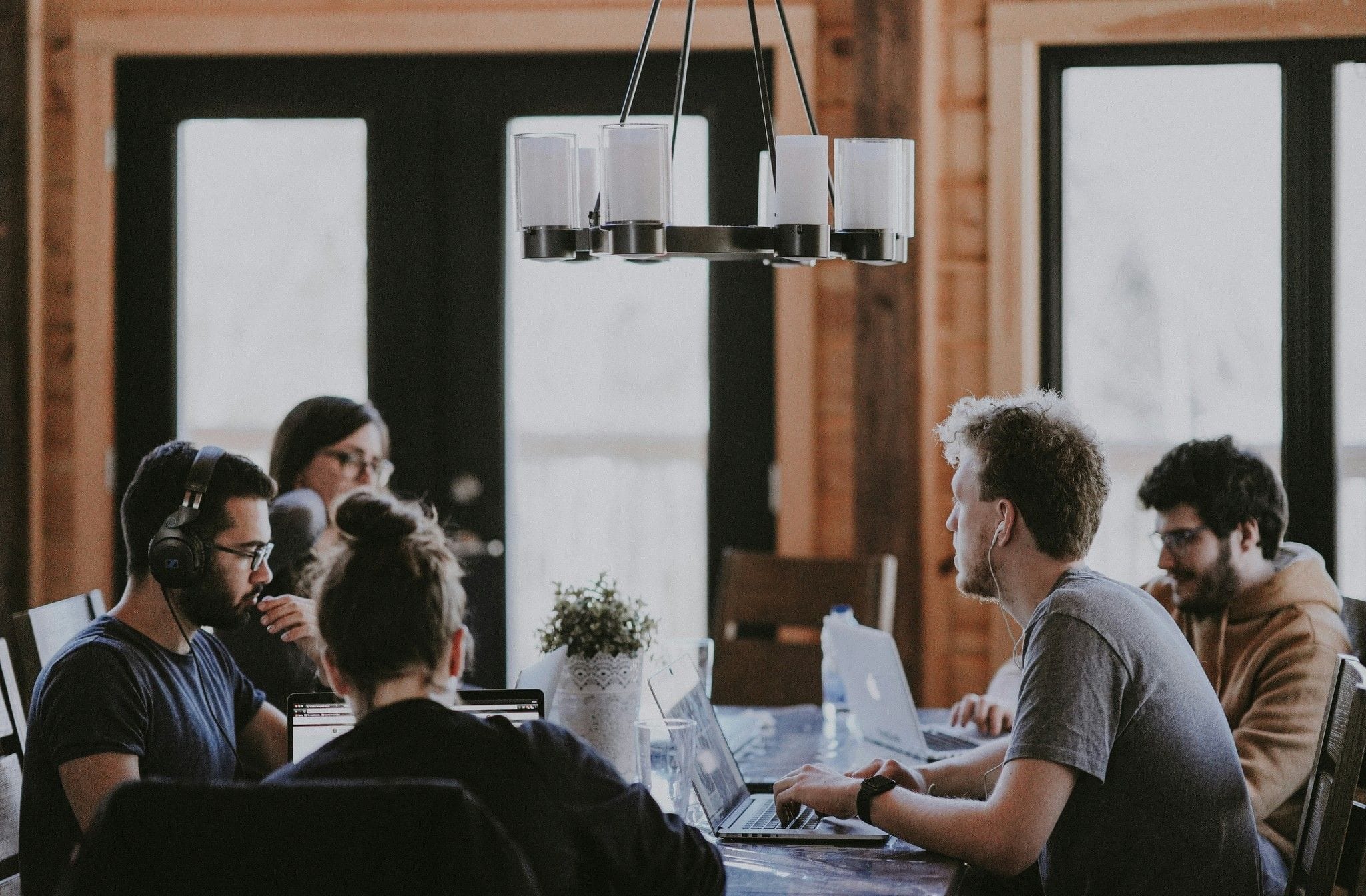 Group of people working on laptops around a table